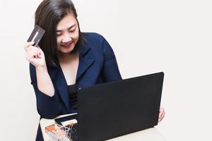 een vrouw met een creditcard die online betaalt, zit op de stoel in de woonkamer thuis op een laptop. het concept van online winkelen. foto