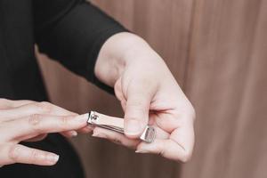 de hand van een blanke vrouw die haar vingernagels knipt met een nagelknipper. concept van hygiëne. foto