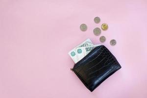 Russische roebels in de portemonnee op een roze achtergrond. duizend biljetten en verschillende munten. plaats voor tekst. ruimte kopiëren. achtergrond voor economisch nieuws. foto