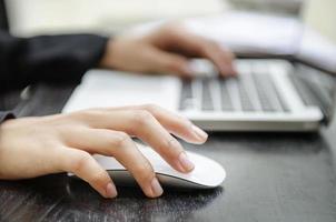 close-up van de handen van een vrouw op een muis en toetsenbord foto