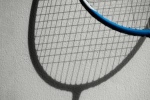 de schaduw van badmintonrackets op witte muur, zachte en selectieve focus, concept voor badmintonsportliefhebber over de hele wereld. foto