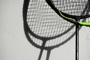 de schaduw van badmintonrackets op witte muur, zachte en selectieve focus, concept voor badmintonsportliefhebber over de hele wereld. foto