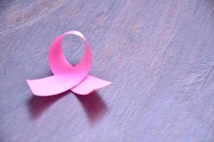 roze lint op houten tafel, concept voor de bestrijding van borstkanker bij vrouwen over de hele wereld. selectieve focus en kopieer ruimte. foto