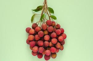 verse lychee vruchten met stengel en bladeren, exotische Aziatische vruchten op roze achtergrond. foto