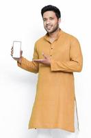 portret van een vrolijke jonge man met kurta op geïsoleerde achtergrond, met een leeg scherm mobiele telefoon. foto