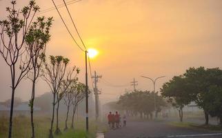 gresik, jawa timur, indonesië, 2022 - mensen die 's ochtends in een woonwijk joggen met zonsopgangachtergrond foto