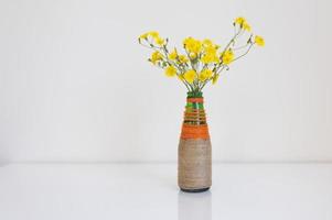 vaas met gele wilde bloemen op een witte tafel foto