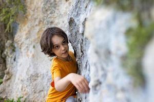 een kleine bergbeklimmer is aan het trainen om een rotsblok te beklimmen foto
