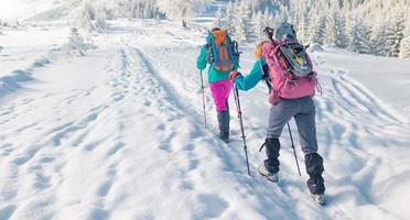 twee vrouwen lopen met sneeuwschoenen op de rugzakken tijdens wintertrekking foto