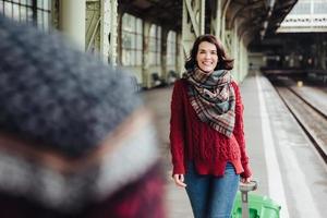 gelukkige vrouw met koffer ontmoet haar man, komt uit het buitenland, heeft een onvergetelijke ontmoeting. verliefd stel ontmoeten elkaar op het station, blij om elkaar weer te zien na een lange scheiding. afstand en afscheid foto