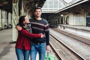 romantisch paar omhelzen op treinstation, afscheid van elkaar. aanhankelijke vrouw omhelst echtgenoot die naar het buitenland gaat, onvergetelijk afscheid. mensen, reizen, afscheid en ontmoeten foto