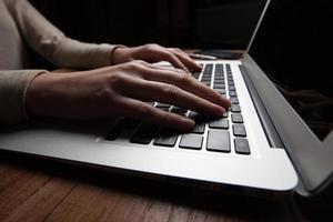 vrouwenhanden die laptop met behulp van bij bureau