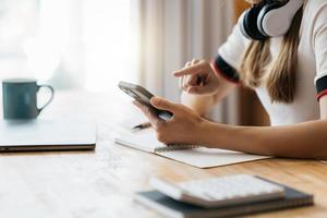 gelukkige aziatische zakenvrouw die een hoofdtelefoon draagt, aantekeningen maakt, praat via een telefonische vergadering, videochat doet op laptop op kantoor, glimlachende chinese ondersteuningsdienstmedewerker schrijft informatie raadpleegt de klant foto