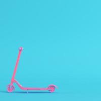roze kick scooter op heldere blauwe achtergrond in pastelkleuren. minimalisme concept foto