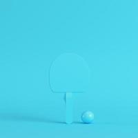 pingpongracket met bal op helderblauwe achtergrond in pastelkleuren. minimalisme concept foto
