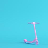 roze kick scooter op heldere blauwe achtergrond in pastelkleuren. minimalisme concept foto