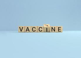 houten kubusblok flip-over woord vaccin naar spuitpictogram op blauwe studioachtergrond. foto
