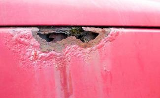 roestige vleugel. corrosie van het lichaam van een rode oude auto na de winter. invloed van reagentia in de winter op een onbeschermde carrosserie. schade aan de linkerkant. foto