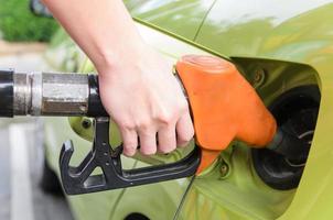 vrouwen houden brandstofpijp aan auto bij benzinestation