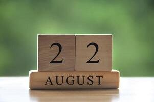 22 augustus kalenderdatum tekst op houten blokken met onscherpe achtergrond park. kopieer ruimte en kalenderconcept foto