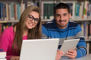 gelukkige studenten die werken met laptop in bibliotheek
