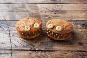 koekjes met roompasta in de vorm van monsters voor halloween-viering. grappige zelfgemaakte gezichten gemaakt van havermoutkoekjes en gekookte gecondenseerde melk. kopieer ruimte foto