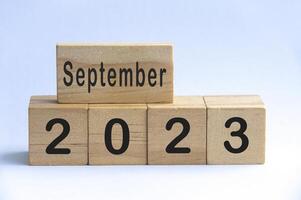 september 2023 tekst op houten blokken met witte kleur achtergrond. kopieer ruimte foto