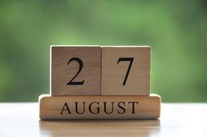 27 augustus kalenderdatum tekst op houten blokken met wazig park als achtergrond. kopieer ruimte en kalenderconcept foto