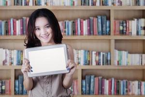 schoolmeisje met een tablet-scherm in de bibliotheek