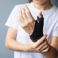 vrouw die haar polspijn vasthoudt omdat ze lang een smartphone of computer gebruikt. de tenosynovitis van de quervain, snijpuntsymptoom, carpaaltunnelsyndroom of kantoorsyndroomconcept foto