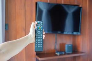 hand met afstandsbediening voor het aanpassen van smart tv in de moderne kamer thuis of in een luxe hotel foto