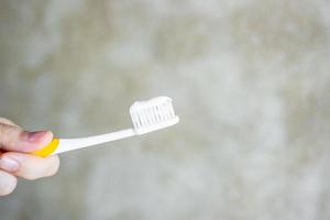 hand met tandenborstels met tandpasta in de badkamer. levensstijl, dagelijkse routine, werelddag voor mondgezondheid en gratis tandheelkundig dagconcept foto