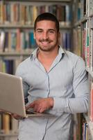 jonge student met behulp van zijn laptop in een bibliotheek