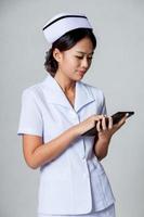 jonge Aziatische verpleegster raak het scherm van een tablet-pc foto