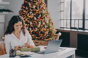 tevreden Europese vrouw kantoormedewerker schrijven kerst brief, wenskaart met vakantiewensen foto