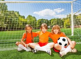 lachende kinderen zitten op gras met voetbal