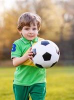 blonde jongen van 4 voetballen met voetbal onl veld foto