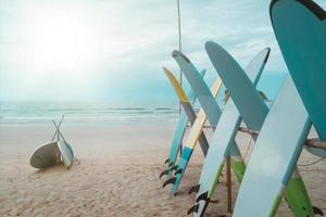 veel surfplanken te huur op het zomerstrand met zonlicht blauwe lucht. foto