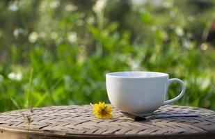 witte keramische kop zwarte koffie met mooie rook boven een kopje en ochtendzon, natuurlijke achtergrond. goedemorgen met een verfrissingsdrankconcept foto