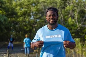 portret van een Afro-Amerikaanse vrijwilliger die geniet van liefdadigheidswerk buitenshuis in een mangroveplantproject foto