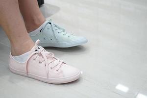 gal probeert pastelkleurige sneakers pasteltint en kleur in sport- en modeschoenenwinkel. foto