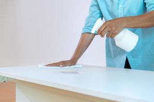 asain meid maakt voor gebruik de tafel schoon met anti-coronavirusreiniger in mistig. foto