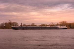 een groot vrachtschip op een rivier in de zonsondergang foto