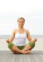 mooie jonge vrouw zitten in yoga pose buitenshuis foto