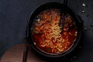 pittige koreaanse instant noedels met wakame zeewier in een zwarte ijzeren pot, koreaans eten in traditionele stijl foto