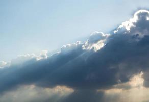 zonnestraal van de zon achter de wolken foto