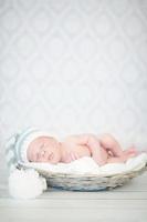foto van een pasgeboren baby opgerold slapen in de mand