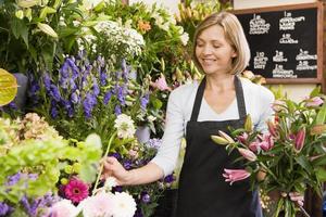 vrouw die bij bloemenwinkel het glimlachen werkt