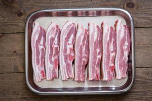buik van varkensvlees in een zilveren dienblad op houten achtergrond