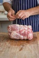 slager die een stuk ham vastmaakt met touw